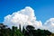 Fluffy clouds over the village. Epic white cloud over green forest