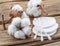 Fluffy cotton ball and cotton swabs and pads on wood.