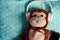 Fluffy monkey toy with headphones and a smartphone on a green blanket