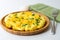 Fluffy omelette from whipped eggs with cheddar cheese and green onion scallions sprinkled on it in a wooden plate.