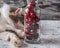 A fluffy tortoiseshell cat is sleeping peacefully on the table. Bottle with a sweet cherry