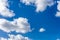 Fluffy white clouds against a bright, colorful blue sky