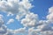 Fluffy white clouds in the blue sky background. White puffy, cotton-like cumulus type of clouds in the sky