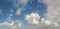 Fluffy white clouds drifting across blue sky panorama