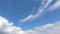 Fluffy white clouds moving fast in time-lapse. Idyllic cloudy heaven background. Timelapse of beautiful clouds in blue sky in even