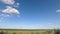 Fluffy white clouds running across the sky over the fields time lapse 4k footage, loop