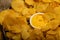 Fluted potato chips in a round plate with sauce in a saucepan in the middle of the plate on a background of homespun fabric with a