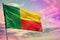 Fluttering Benin flag on colorful cloudy sky background. Prosperity concept