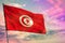 Fluttering Tunisia flag on colorful cloudy sky background. Prosperity concept