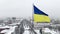 Fluttering on wind flag of Ukraine against background of winter Dnipro city and snowy street from a bird eye view