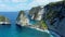 Fly around cliff and rocks over ocean along coast