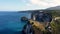 Fly around cliff and rocks over ocean along coast