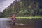 Fly fishing angler makes cast while standing in water