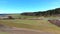 Fly over autobahn near forest with town on horizon.Aerial video of autobahn through green meadow and forest