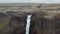 Fly over edge of rock. Revealing tall waterfall. Mass of white water falling down to depth. Amazing preserved Nordic