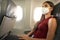 Fly Safe. Young business woman wearing KN95 FFP2 mask is traveling on airplane. New normal travel after coronavirus pandemic