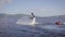 Flyboard surfer is flying over lake surface, plunging and lifting up, pushing by water flows, in summer vacation