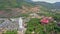 Flycam Approaches Large Buddha Statue by Temple against Hills