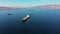 Flycam films long white freight vessel crossing clear water