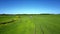 Flycam follows tractor trace on vast green field