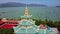 Flycam moves around Buddhist pagoda roof against sea bay