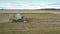 Flycam moves close to combine gathering wheat leaving straw
