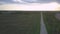 Flycam moves over long wide highway among fields at twilight