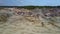 Flycam rises above clay pit by forest under blue sky