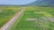 Flycam Shows Road with Driving Car among Rice Fields
