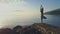 Flycam View Girl on Rock Beach against Hilly Landscape