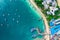 Flying above busy tropical island port filled with boats and ferries. Countless ships sail to and from bustling harbor on exotic