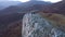 Flying above a couple relaxing on a mountain cliff. Aerial