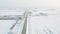 Flying above a large field covered in snow and a road in the middle of it