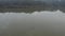 Flying above the surface of a clear reflective lake with flock of bird in water