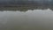 Flying above the surface of a clear reflective lake with flock of bird in water