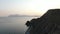 Flying along the beach at the foot of the hill towards. On the horizon against the backdrop of a pink sunset mountains