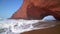 Flying through the arch on Legzira beach with arched rocks on the Atlantic coast in Morocco