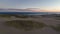 Flying backwards over deserted sand dunes on coast at sunrise