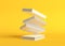 Flying books on pastel yellow background