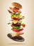 Flying burger ingredients above wooden board on brown background