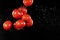 Flying cherry tomatoes, isolated on black background.