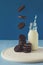 Flying chocolate cookies with milk on blue paper background. Breakfast food