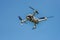 Flying drone with camera on a blue background with copy space. Airborne quadcopter. Also known as a drone or UAV.