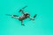 Flying drone with camera on turquoise background with copy space. Airborne quadcopter. Also known as a drone or UAV.