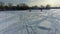 Flying with a drone at low angle over the tire tracks towards camping trailers on the frozen river a someone walking in the white