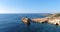 Flying drone over the coastline of the island overlooking an old rusty sunken ship