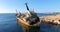 Flying drone over the coastline overlooking an old rusty sunken ship or liner