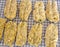 Flying fish breaded and resting on a metal rack prior to frying