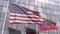 Flying flags of the USA and Venezuela in front of a modern skyscraper