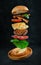 Flying hamburger with ingredients on dark stone background. Creative still life concept